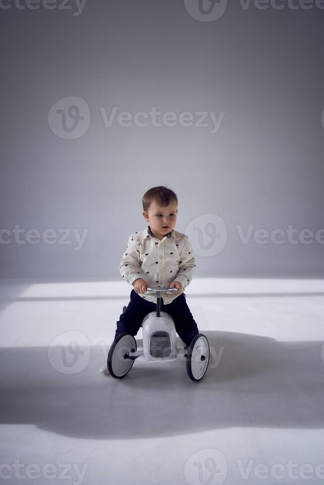 une bambin est avec enthousiasme en jouant avec le sien jouet voiture sur le sien anniversaire photo