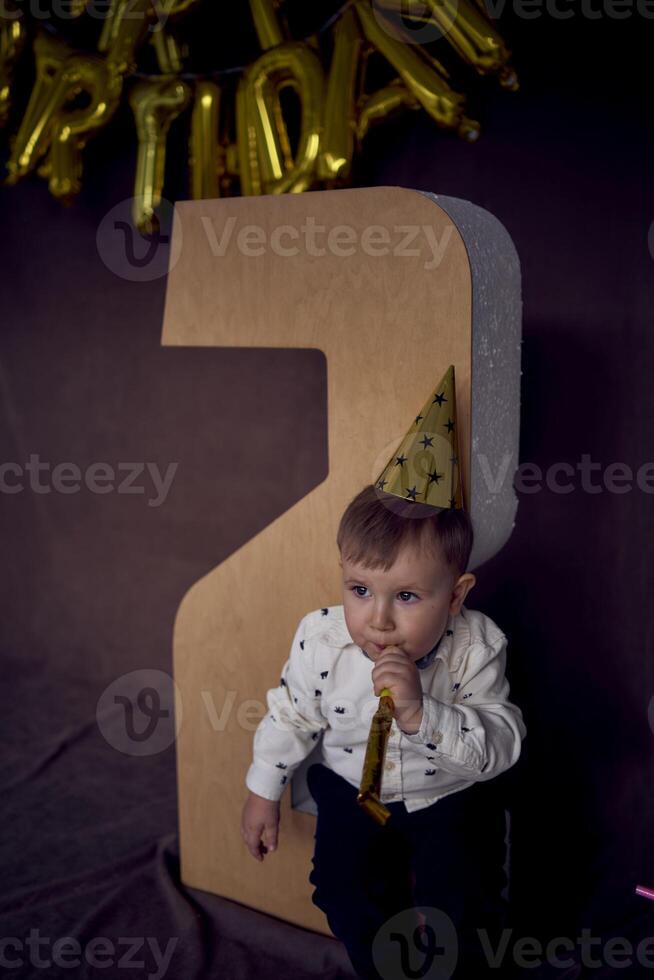 une bambin dans une fête casquette coups une sifflet flûte photo