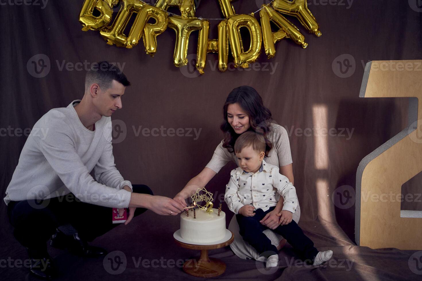 père lumières bougies sur le sien fils seconde anniversaire gâteau photo