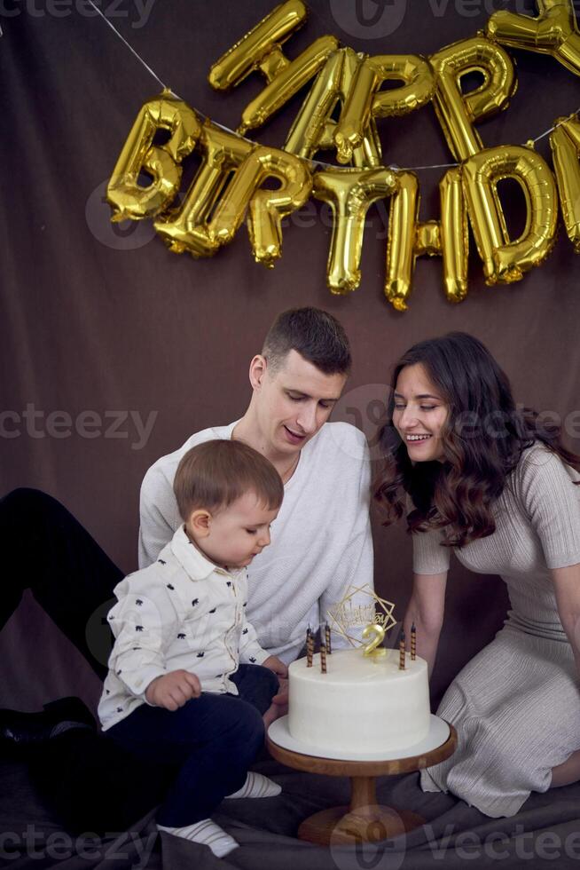 émotif Parents regarder comme leur fils coups en dehors le bougies sur le anniversaire gâteau photo