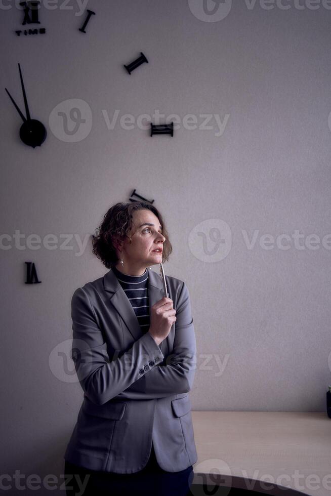 femme permanent dans Bureau dans de face de l'horloge photo