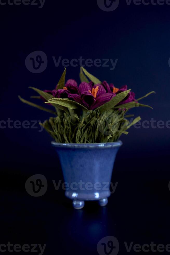 papier fleurs dans une bleu vase sur une noir Contexte photo