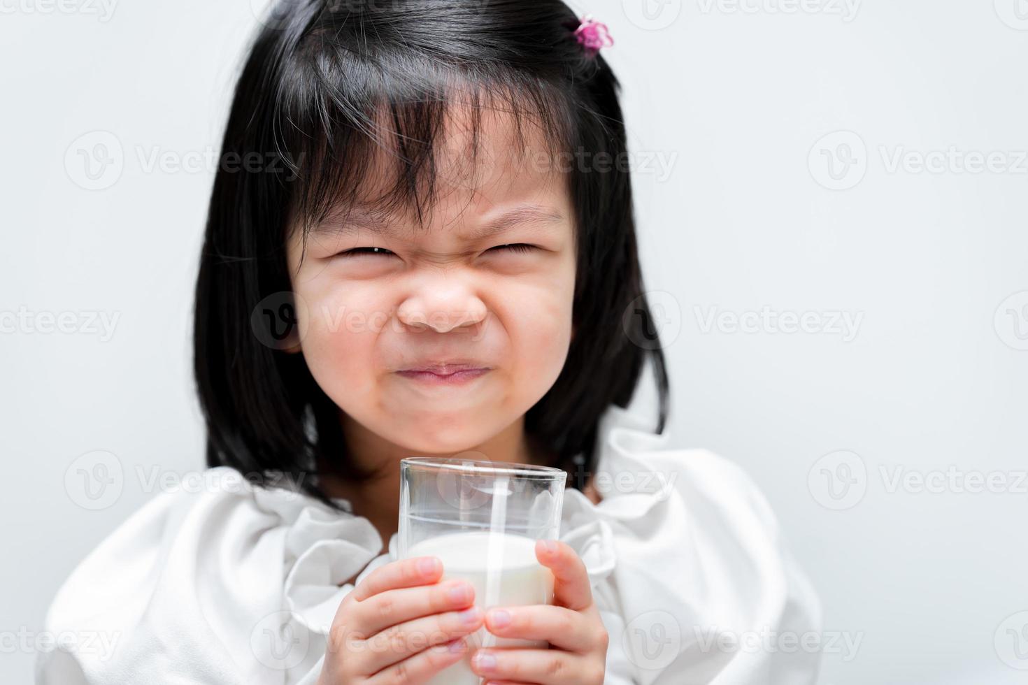 jolie fille boit du lait en verre. les enfants aiment boire du lait. enfant de 4 ans. fond blanc isolé. photo