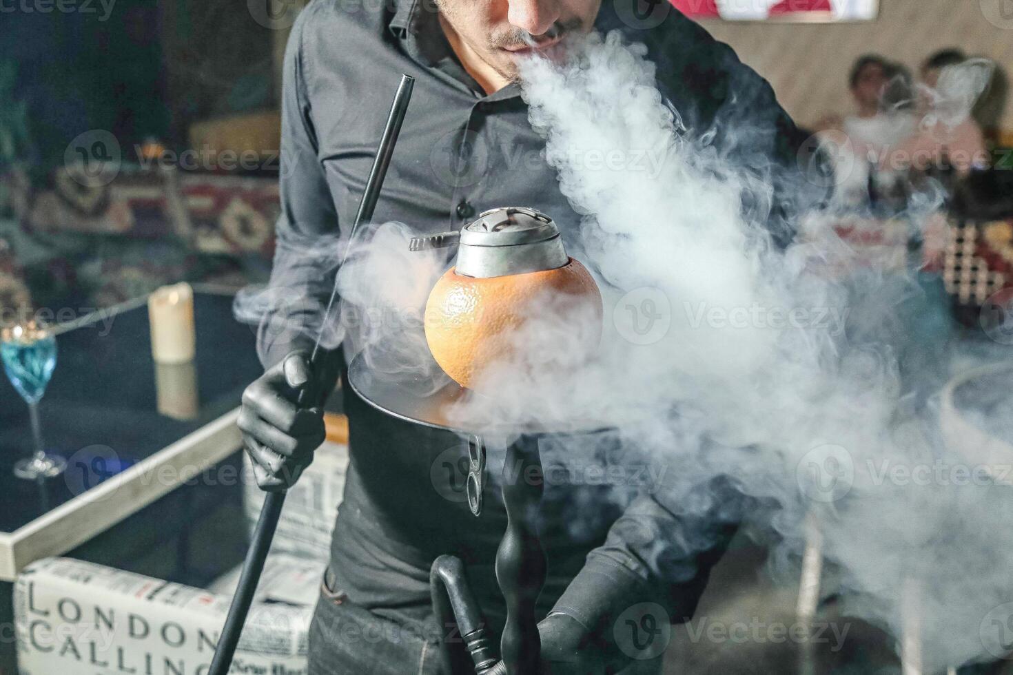 homme dans noir chemise en portant bouilloire avec fumée photo