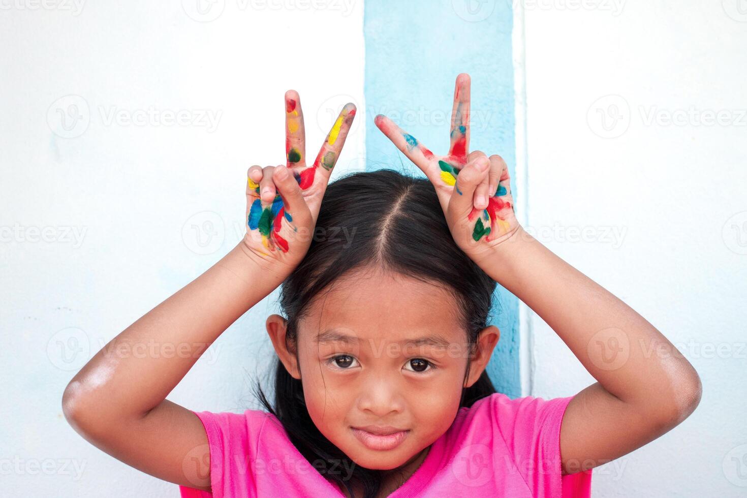 mignonne peu fille avec coloré peint mains sur mur Contexte photo