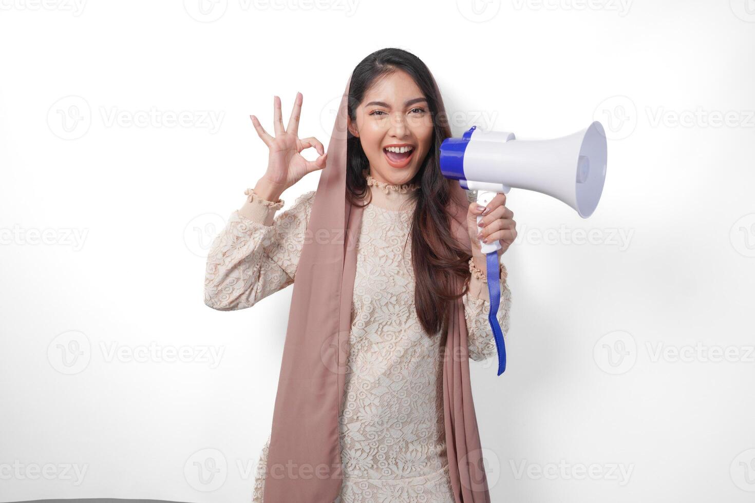 attrayant Jeune asiatique musulman femme dans voile hijab faire des gestes D'accord d'accord, bien signe avec sa les doigts tandis que en criant à mégaphone. Ramadan et eid mubarak concept photo