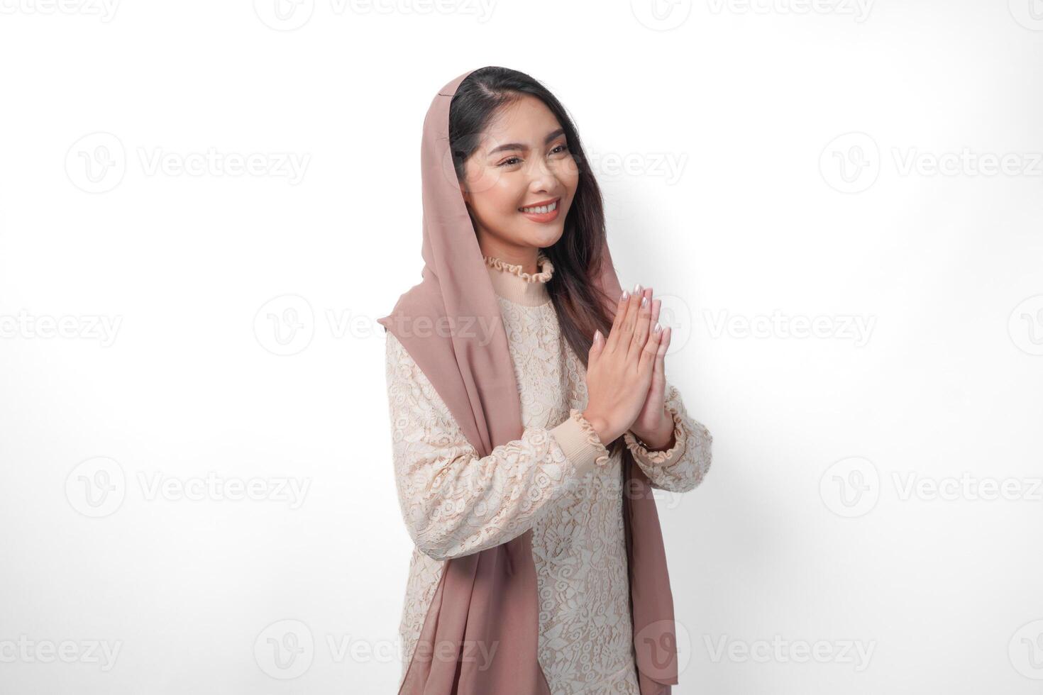 magnifique asiatique musulman femme portant foulard voile hijab souriant à le caméra et faire des gestes traditionnel salutation isolé plus de blanc Contexte photo