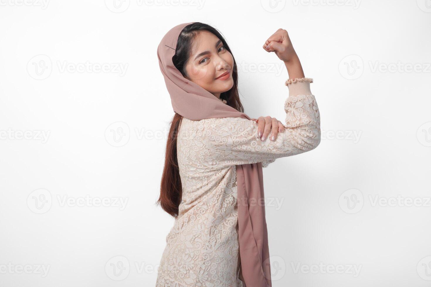 Jeune asiatique femme dans foulard voile hijab plein de confiance élevage une poing en haut main signe geste, affichage une fort fille pose. Ramadan concept photo