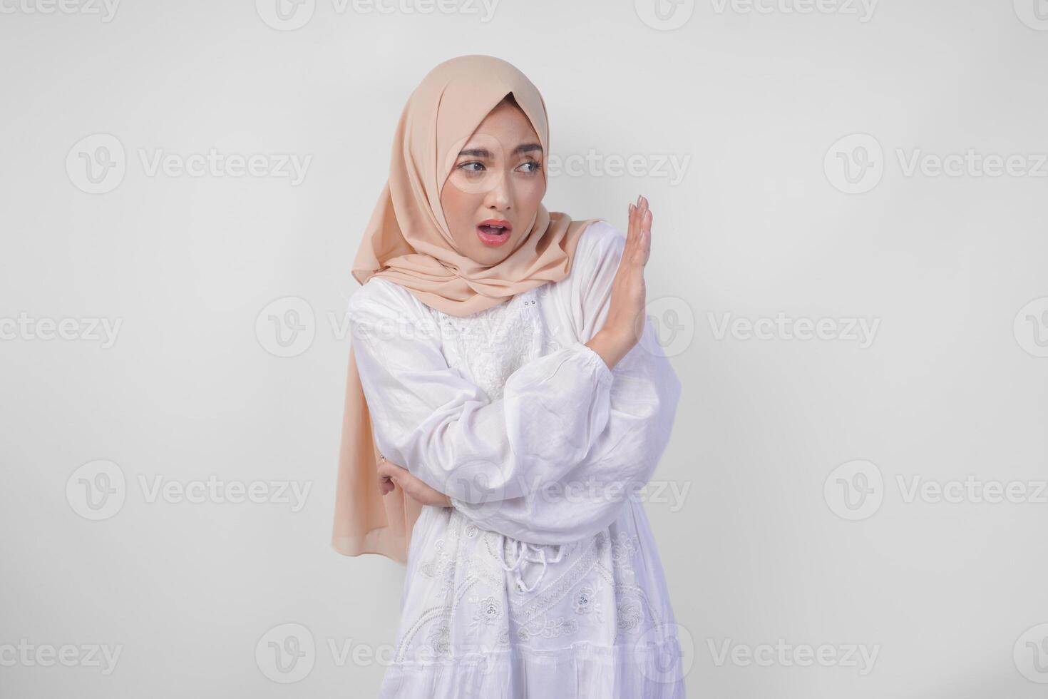 Jeune asiatique musulman femme portant hijab et blanc robe faire des gestes une non rejet, refuser en utilisant mains à le copie espace sur la gauche côté, isolé par blanc Contexte. Ramadan et eid mubarak concept photo