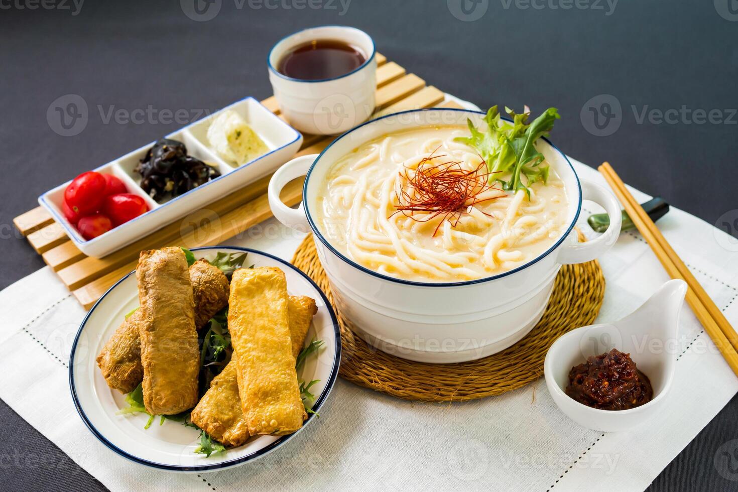 poisson croustillant rouleau poisson udon dans riches poisson soupe nouille avec le Chili sauce et baguettes servi dans bol isolé sur serviette de table côté vue de Japonais nourriture sur table photo