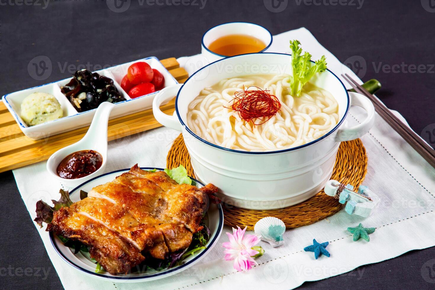 croustillant grillé poulet steak, poisson udon dans riches poisson soupe nouilles servi dans bol avec le Chili sauce et baguettes isolé sur serviette de table côté vue de Japonais toto sur table photo