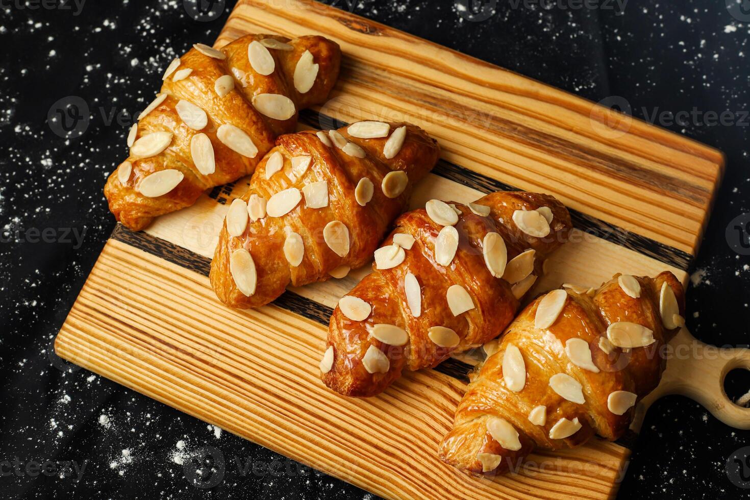 amande croissant Garniture avec des noisettes servi sur en bois planche Haut vue de français petit déjeuner cuit nourriture article photo