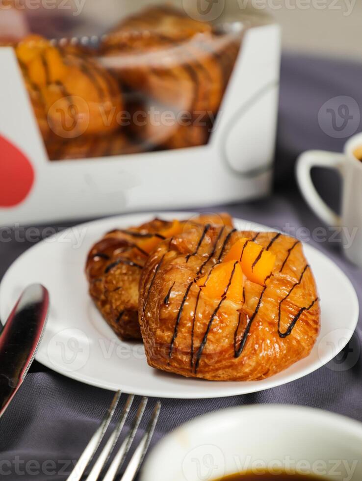 pêche danois Pâtisserie bouffée servi dans assiette avec tasse de noir café isolé sur serviette de table avec fourchette et couteau côté vue de français petit déjeuner cuit nourriture article sur gris Contexte photo