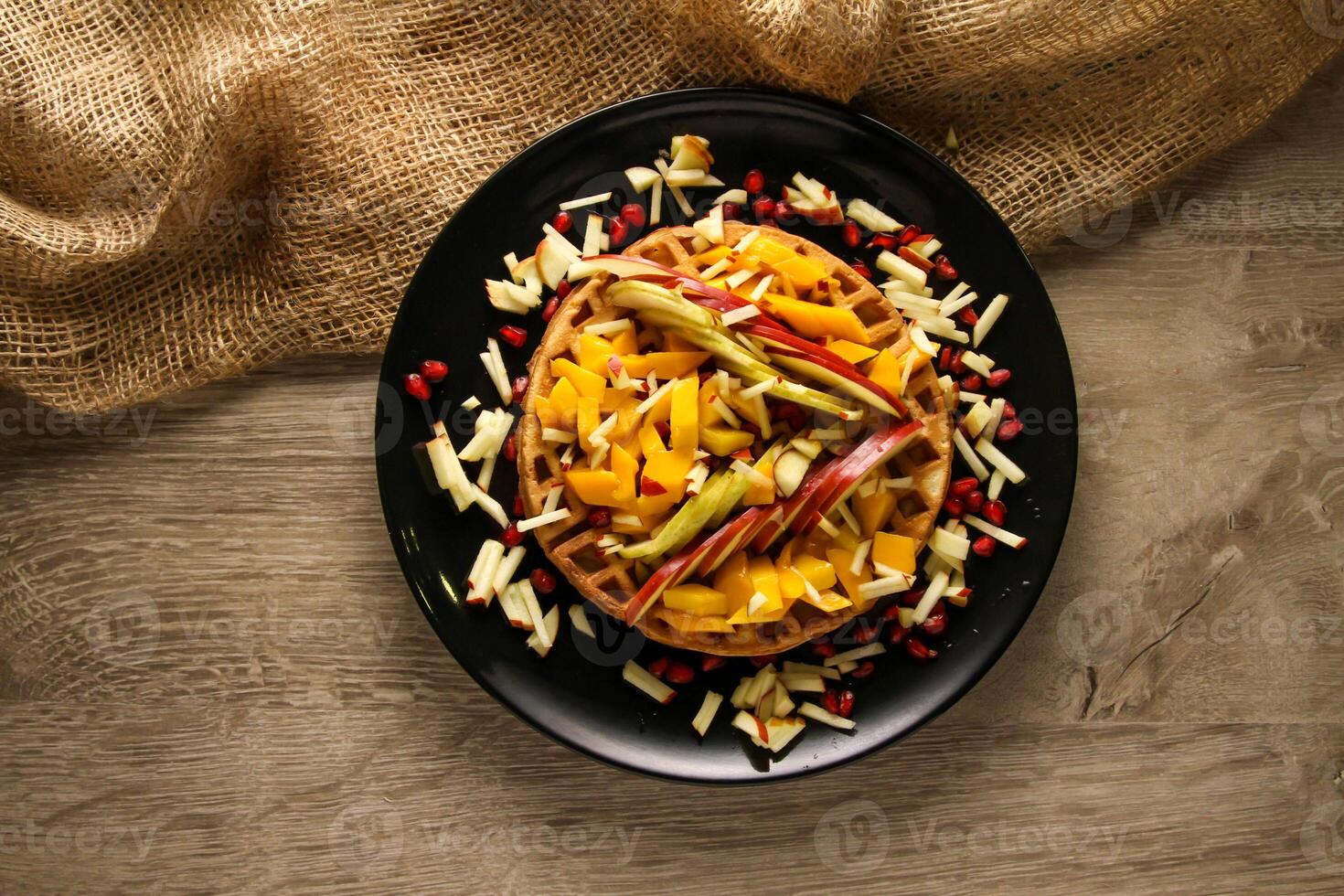 gaufre avec mélanger des fruits comprendre pomme, mangue, Grenade des graines et banane servi dans plat isolé sur table Haut vue de café casse-croûte photo