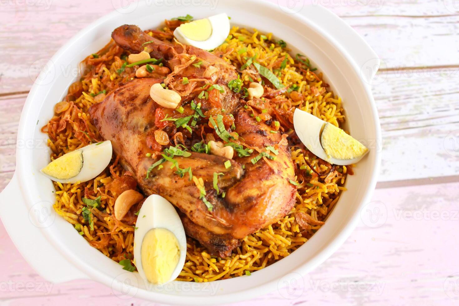 poulet machboos mandi Pulao riz biryani avec frit oignon, anacardier écrou et bouilli Oeuf servi dans pot plat isolé sur en bois table Haut vue arabe épicé nourriture photo