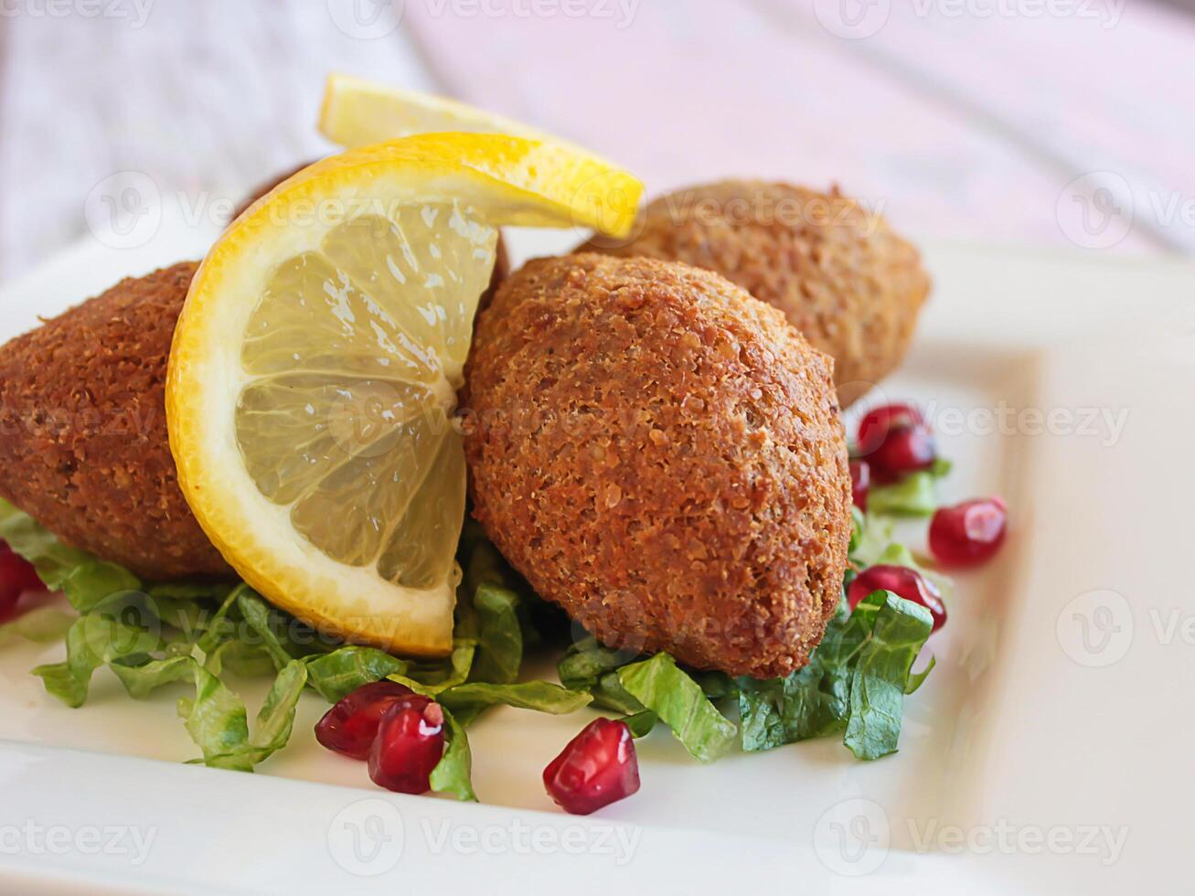 kebbah, kibbé, kibbe ou kubbeh avec citron tranche et Grenade des graines fermer servi dans plat isolé sur table côté vue de arabe Fast food photo