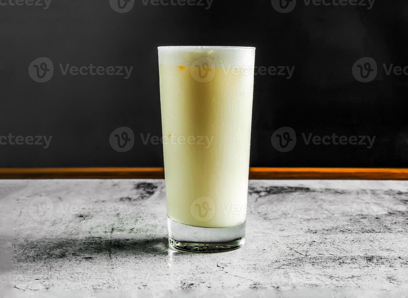 sucré lassi avec yaourt, sucre, l'eau et la glace servi dans verre côté vue sur gris Contexte boisson photo