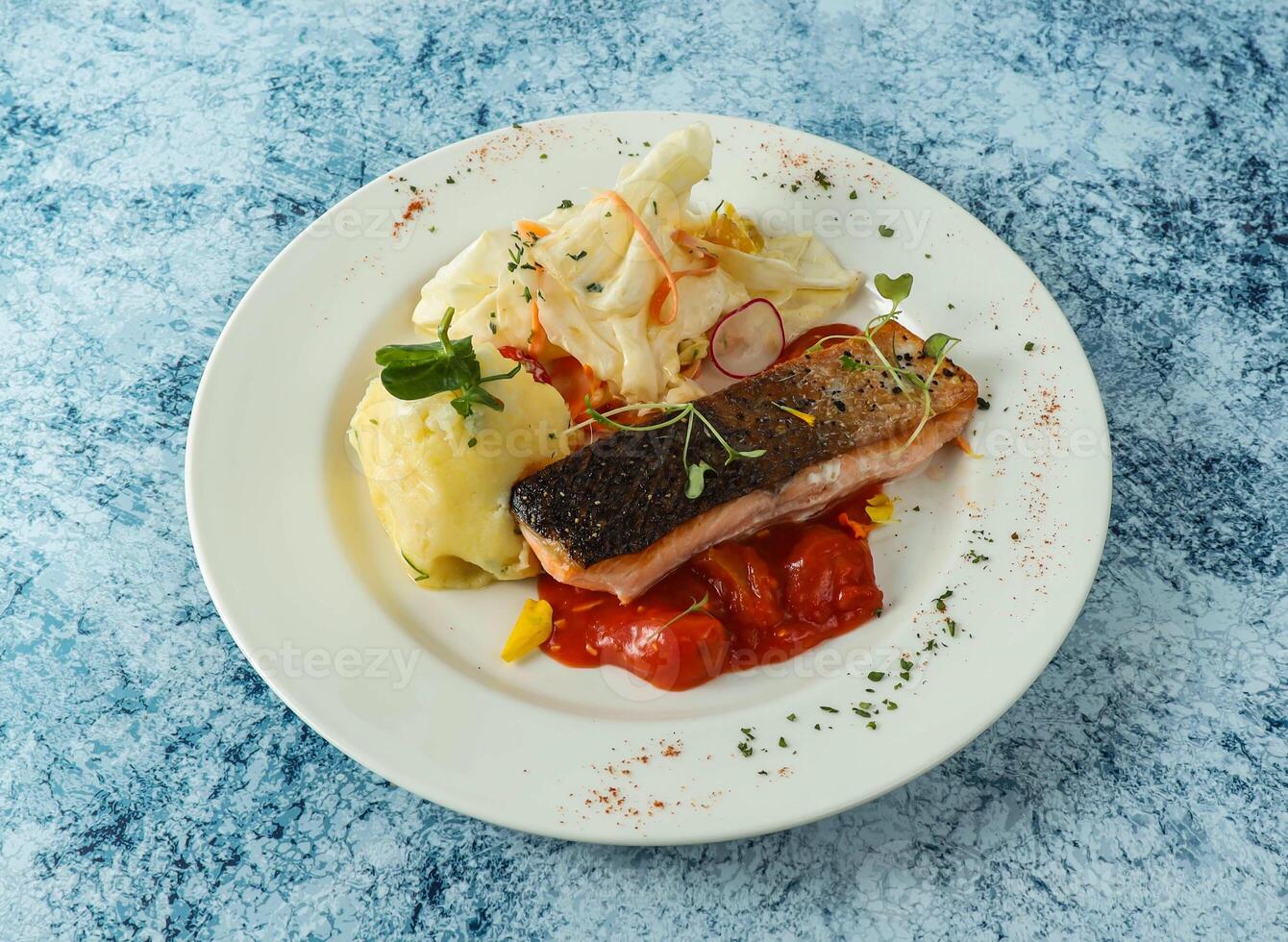 grillé Saumon poisson avec tomate et en purée Patate servi dans assiette isolé sur Contexte Haut vue de italien nourriture photo