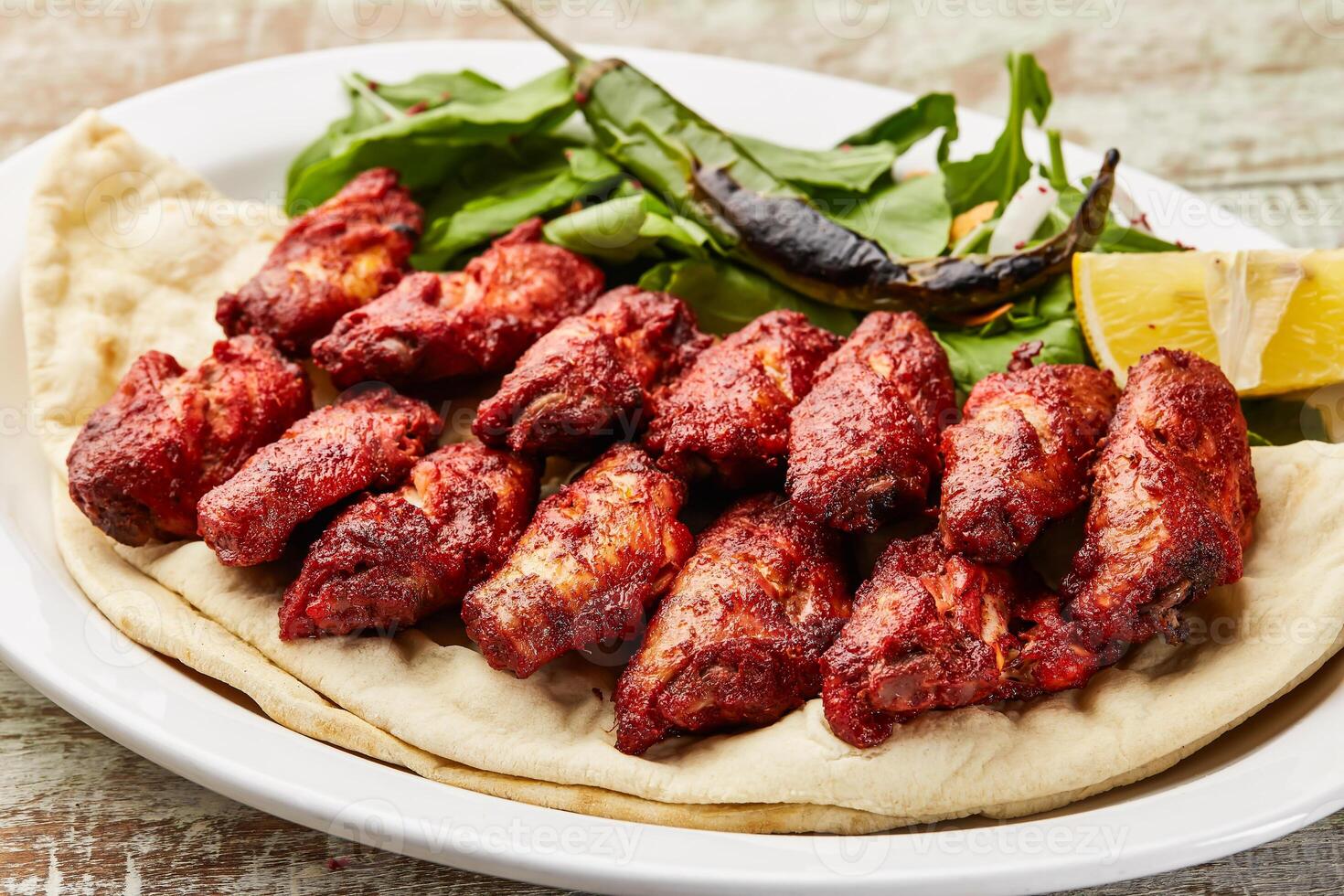 épicé poulet ailes avec citron tranche et salade servi dans plat isolé sur table Haut vue de arabe nourriture photo