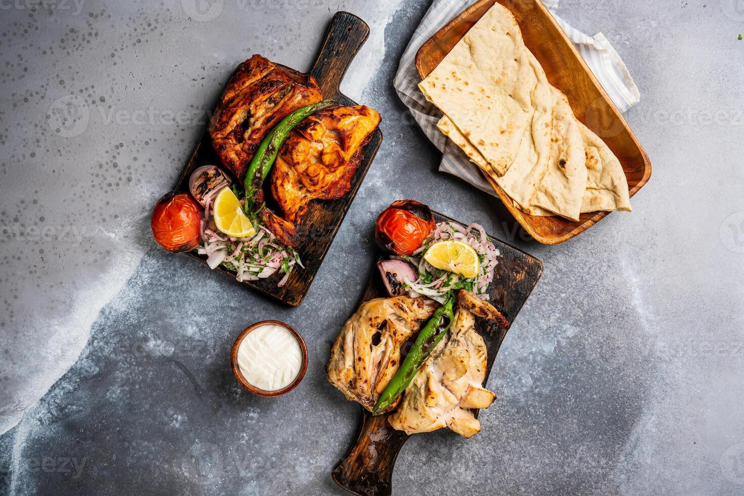 moitié grillé poulet plat gril avec Pita pain, Nan, tandoori rôti, raita, tremper et salade, tomate oignon et citron servi dans en bois planche Haut vue sur Contexte épicé barbecue photo