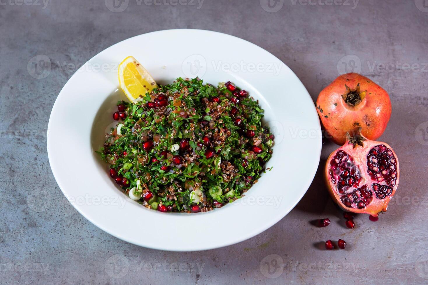 quinoa salade avec Grenade des graines et citron vert tranche servi dans plat isolé sur gris Contexte Haut vue de Bahreïn nourriture photo