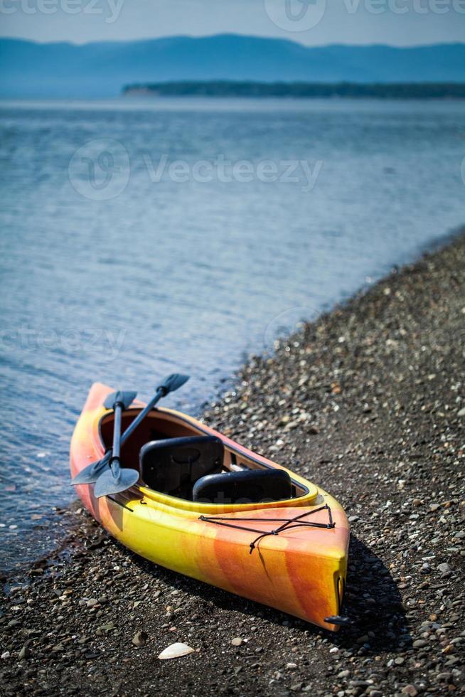 kayak orange et jaune avec des rames au bord de la mer photo