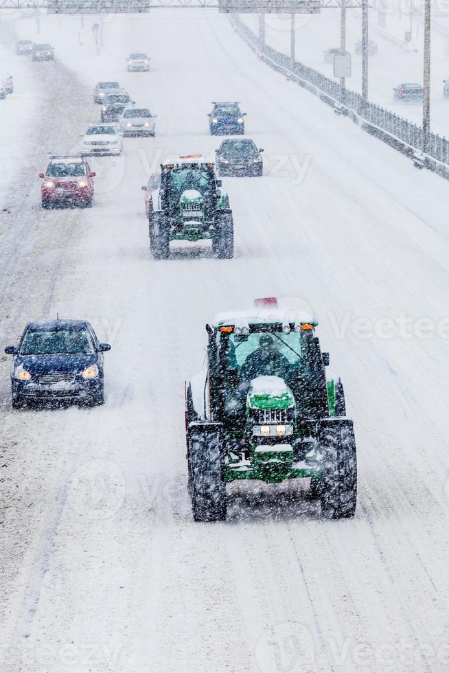 deux chasse-neige et voitures pendant une tempête de neige photo