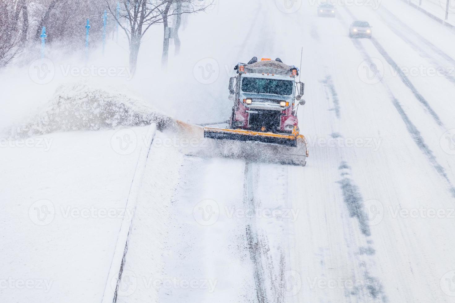 chasse-neige enlevant la neige de l'autoroute pendant une tempête de neige photo
