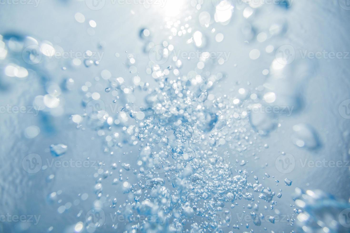 bulles d'air sous-marines abstraites remontant à la surface de l'eau avec des rayons de soleil photo