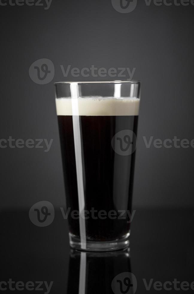 Projet d'azote frais et crémeux pinte de bière noire stout sur fond noir photo