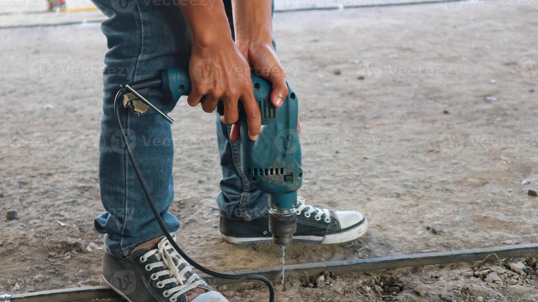 travailleur de la construction à l'aide d'un marteau-piqueur forant une surface en béton photo