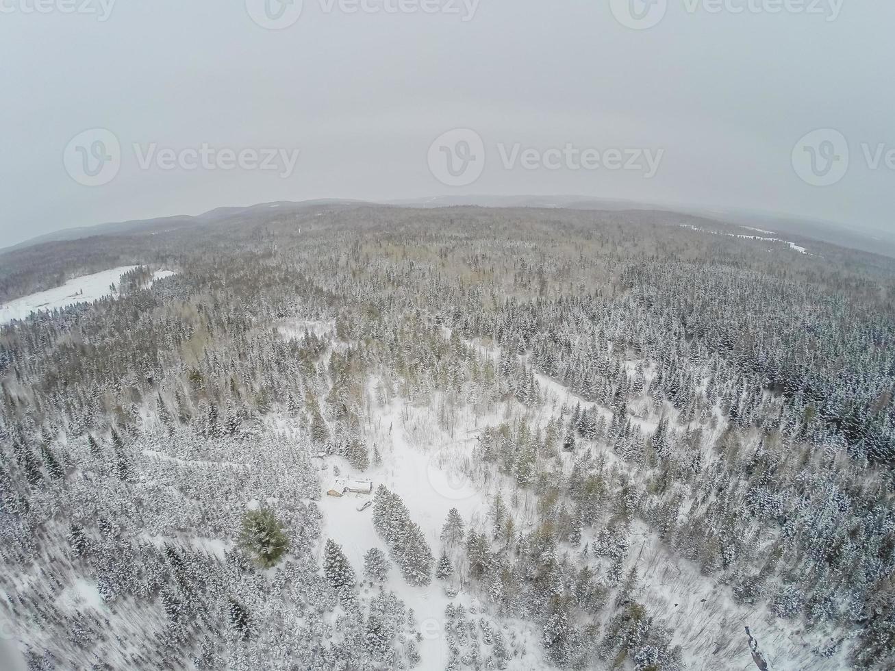 vue aérienne de la forêt et de la petite cabane en bois de rondins canadienne pendant l'hiver. photo