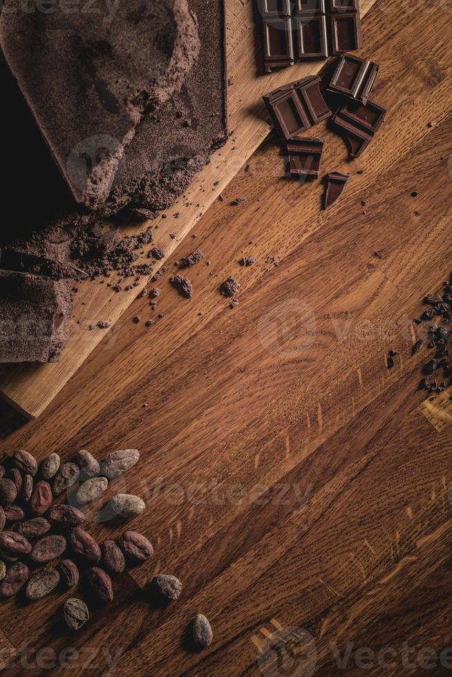 arrangement de vue de dessus de table sucrée de fèves de cacao, de nibs et de barres de chocolat photo