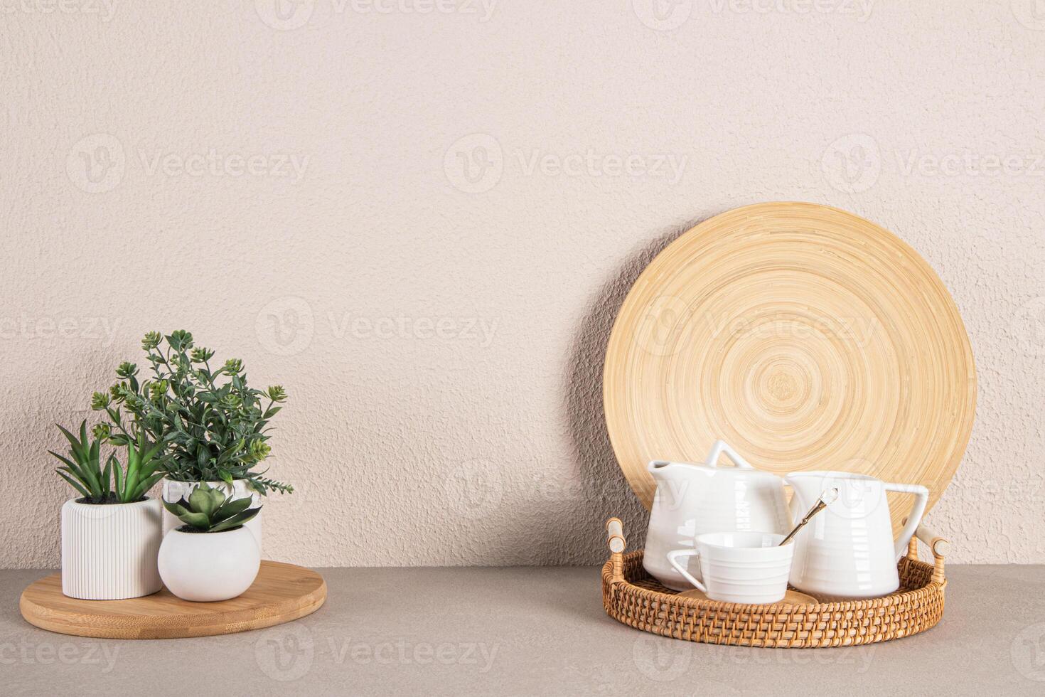 ensemble de céramique thé fête ustensiles sur une osier plateau et mis en pot plantes d'intérieur sur une pierre plan de travail de une moderne cuisine. minimalisme photo