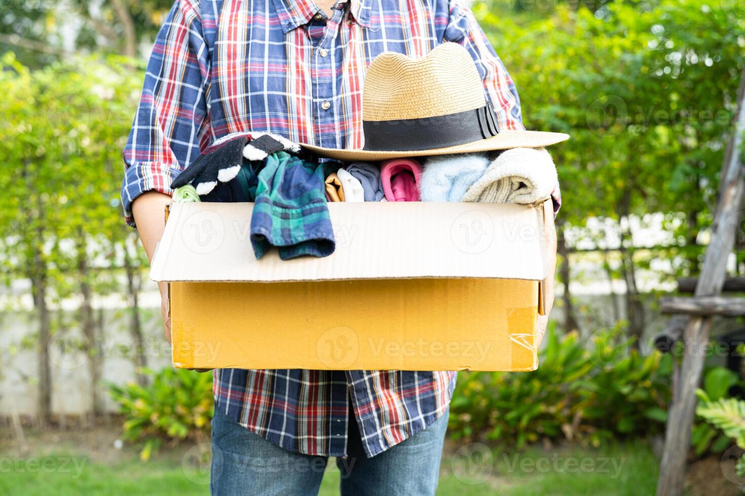 bénévole femme fournir Vêtements don boîte avec utilisé vêtements et poupée à soutien Aidez-moi pour réfugié, sans abri ou pauvres gens dans le monde. photo