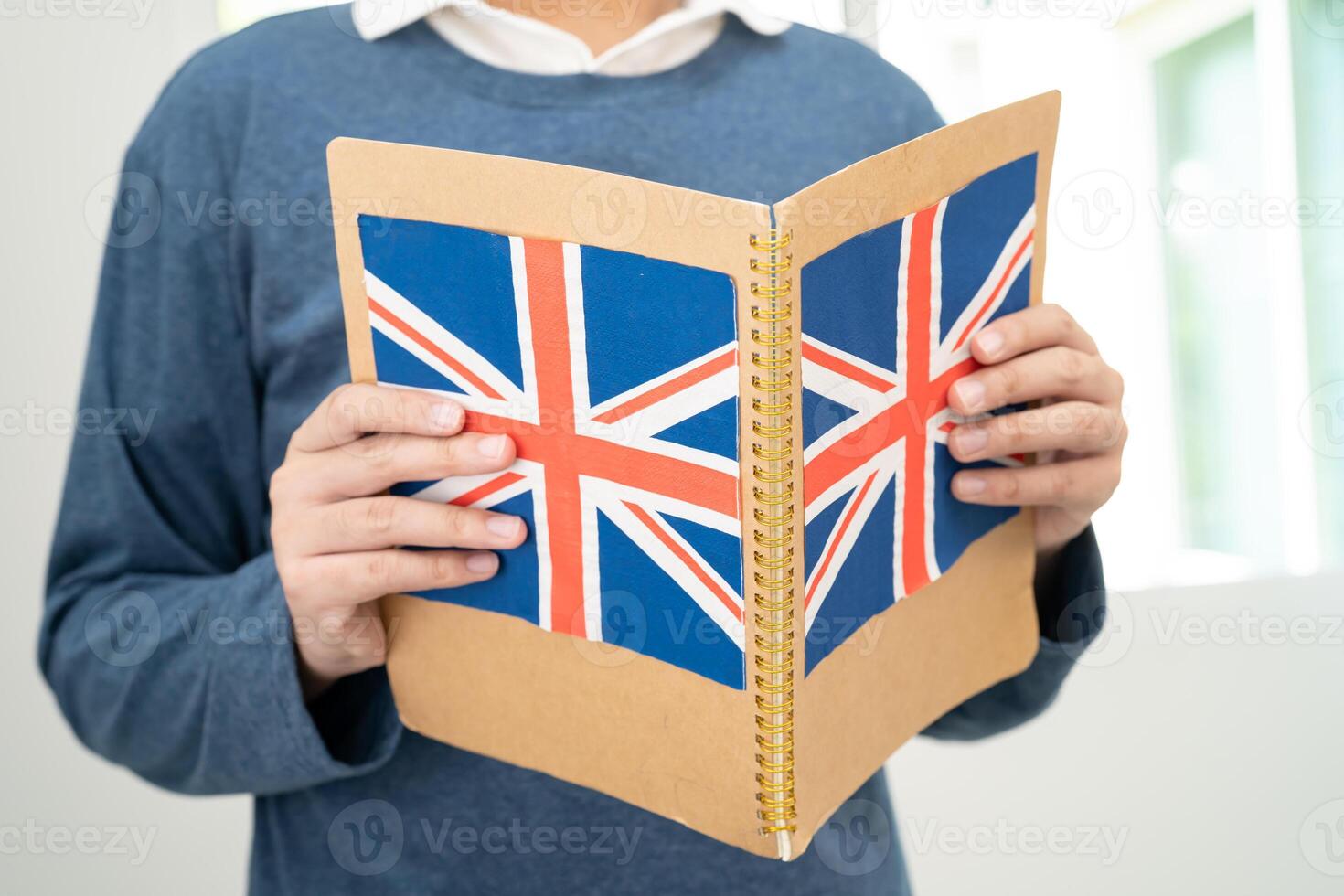 apprendre Anglais langue, asiatique adolescent étudiant tenir livre avec drapeau dans cours à école. photo