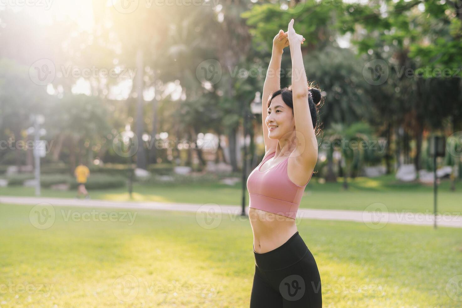 bien-être et en bonne santé mode de vie portrait de 30s asiatique femme dans rose tenue de sport. en train de préparer et élongation bras muscles avant le coucher du soleil courir dans le parc. aptitude à l'extérieur et embrasse équilibré vie. photo