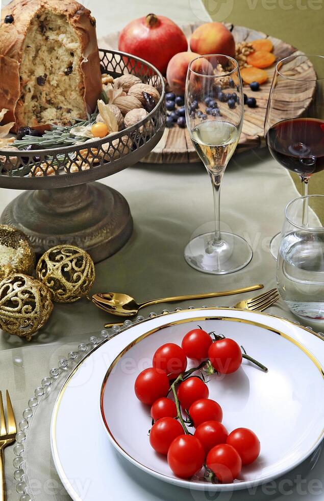 assiette avec tomates sur table avec panetton, lunettes, fruit et du vin photo