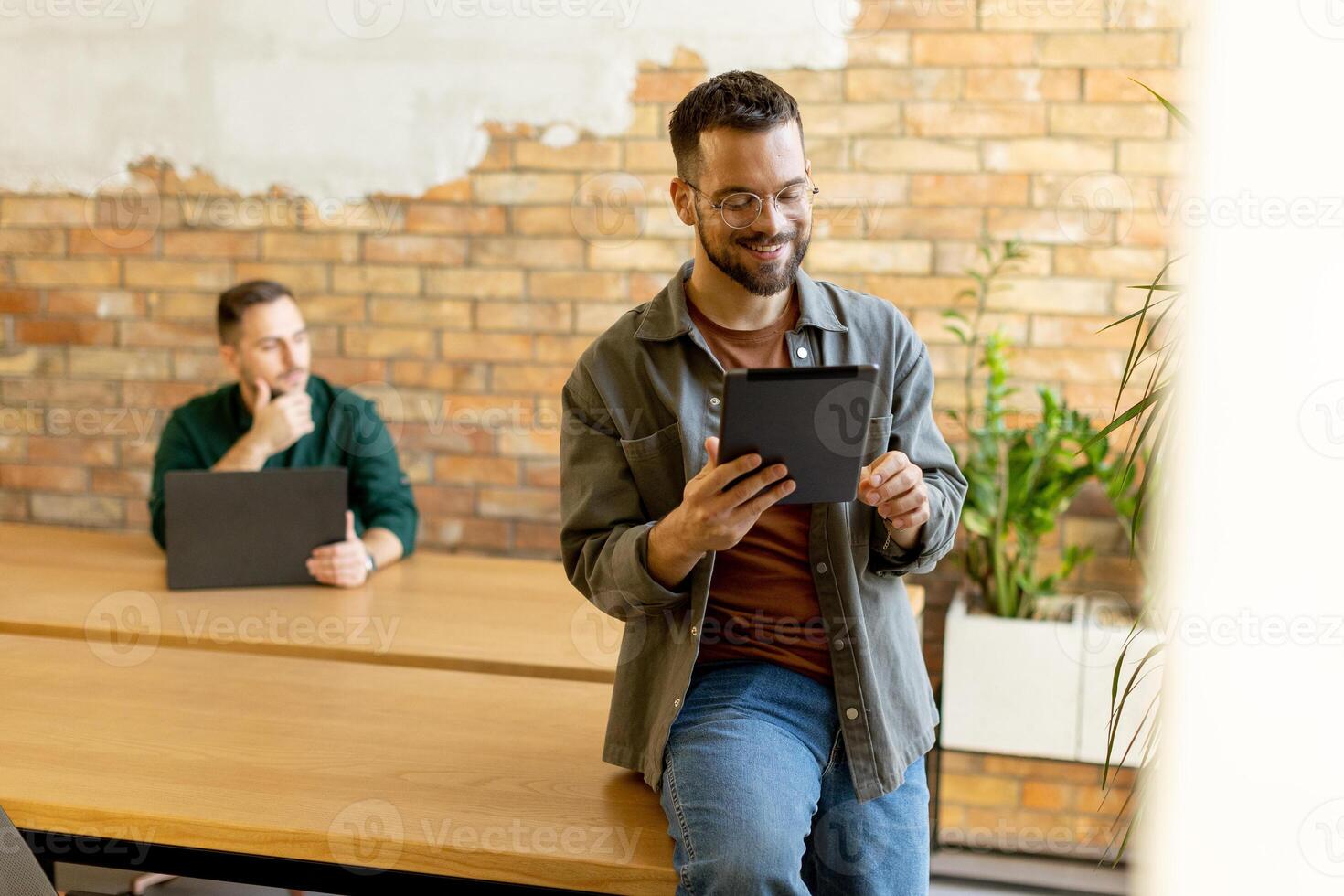 engagé collègues dans une moderne espace de travail, réflexion avec tablette et portable photo