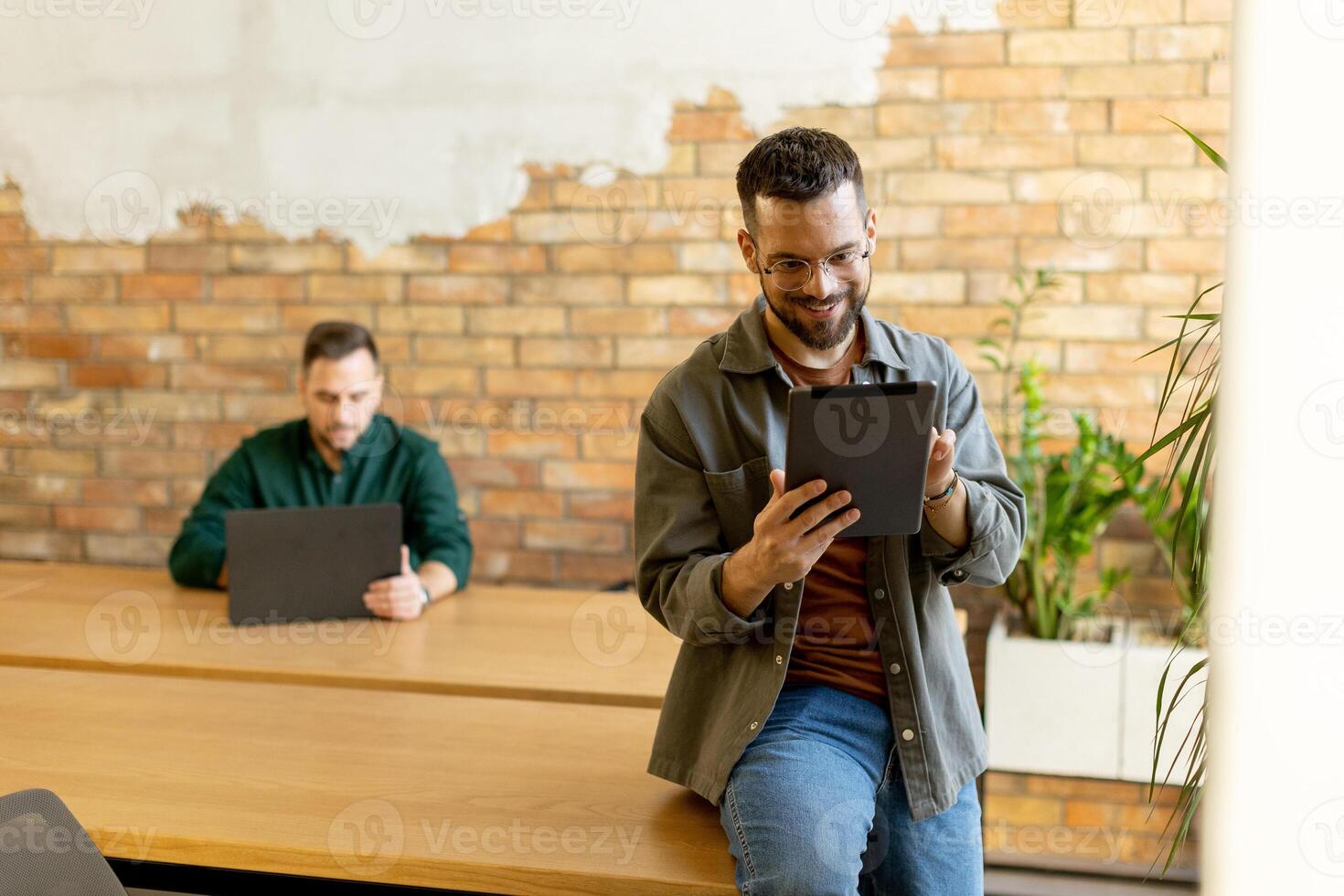 engagé collègues dans une moderne espace de travail, réflexion avec tablette et portable photo