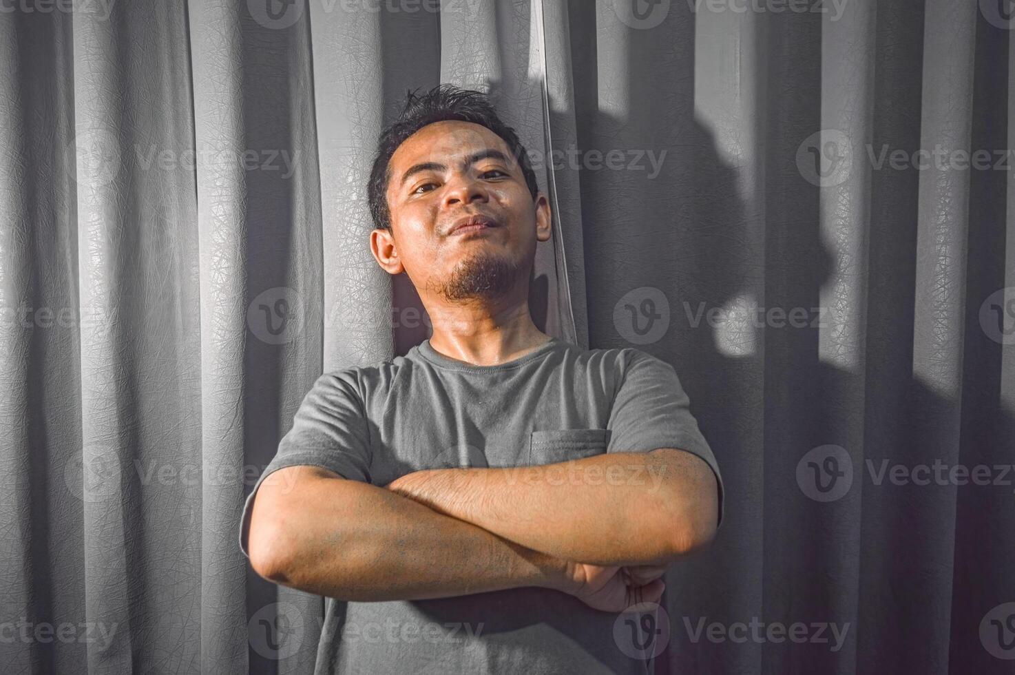 Beau asiatique homme sentiment fier portant gris T-shirt sur rideau Contexte photo
