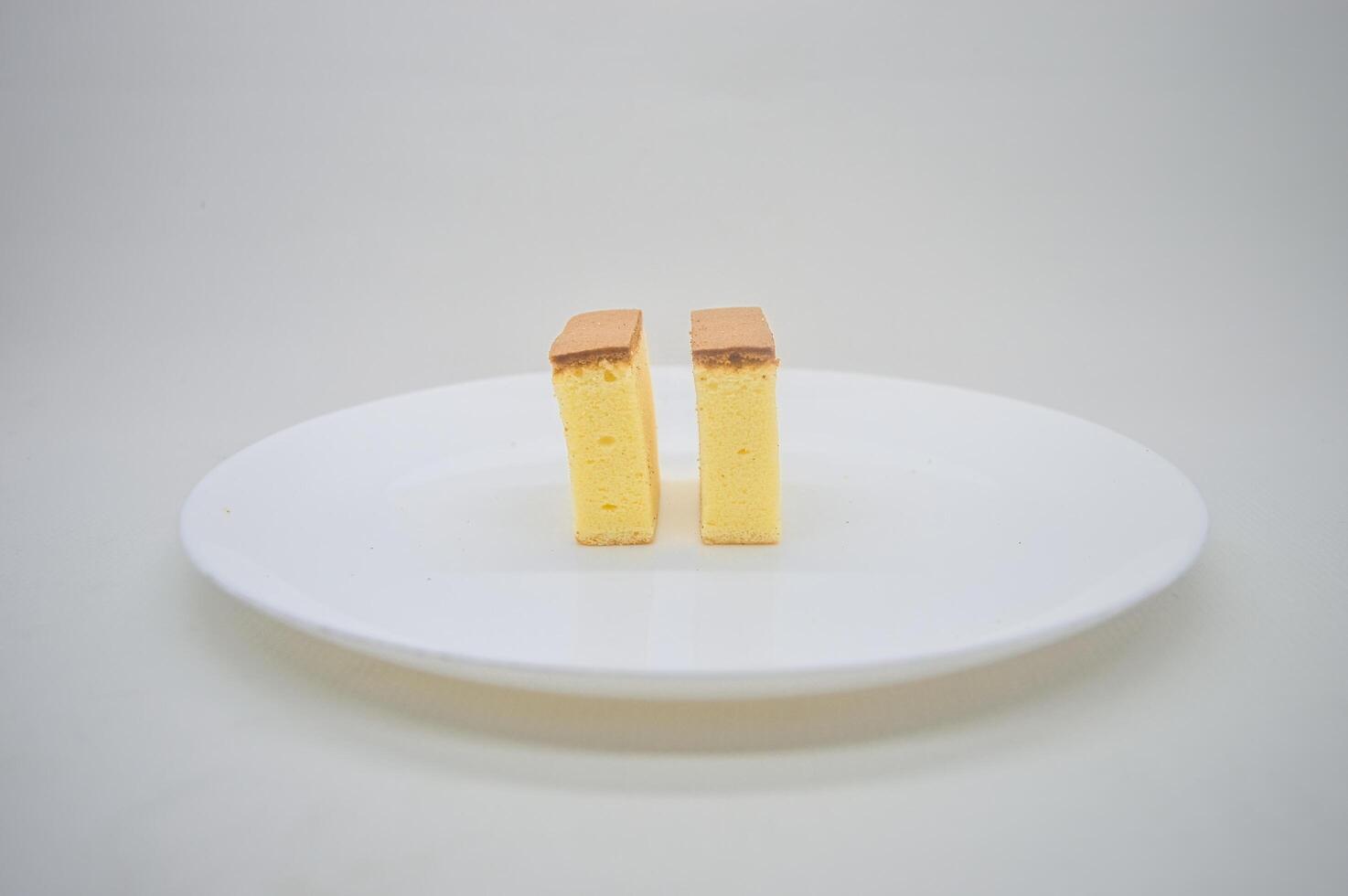 deux tranches de fromage gâteau sur une blanc assiette avec une plaine Contexte photo