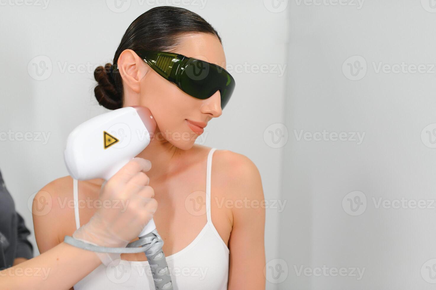 fermer de esthéticien donnant épilation laser traitement sur femme visage photo