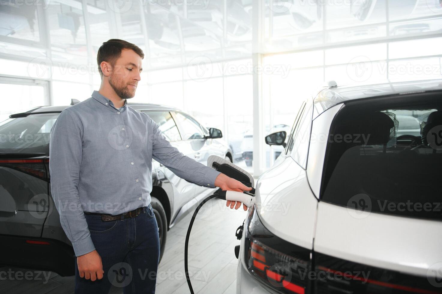 barbe homme en essayant une Nouveau mise en charge câble avec une voiture mise en charge station à le moteur concession. concept de achat électrique véhicule. intelligent écologique vivant photo