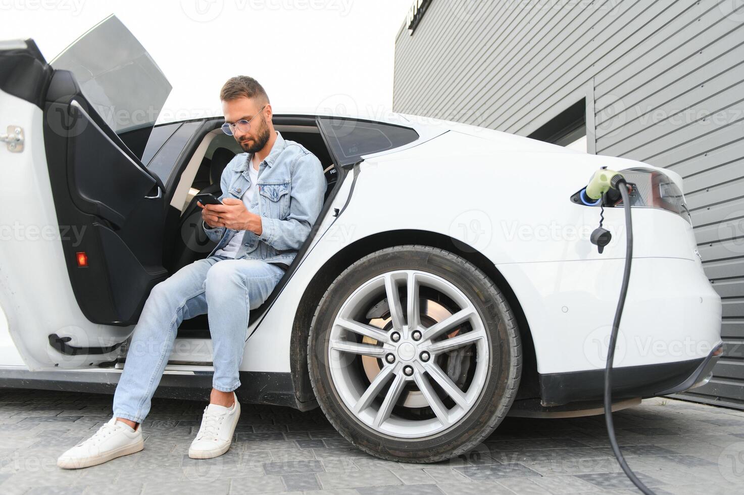 content homme en utilisant intelligent téléphone et mise en charge voiture à véhicule mise en charge station photo