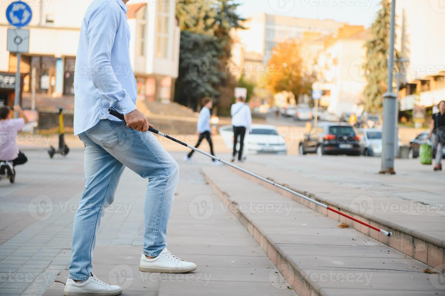 Jeune Beau aveugle homme en marchant avec bâton dans ville photo