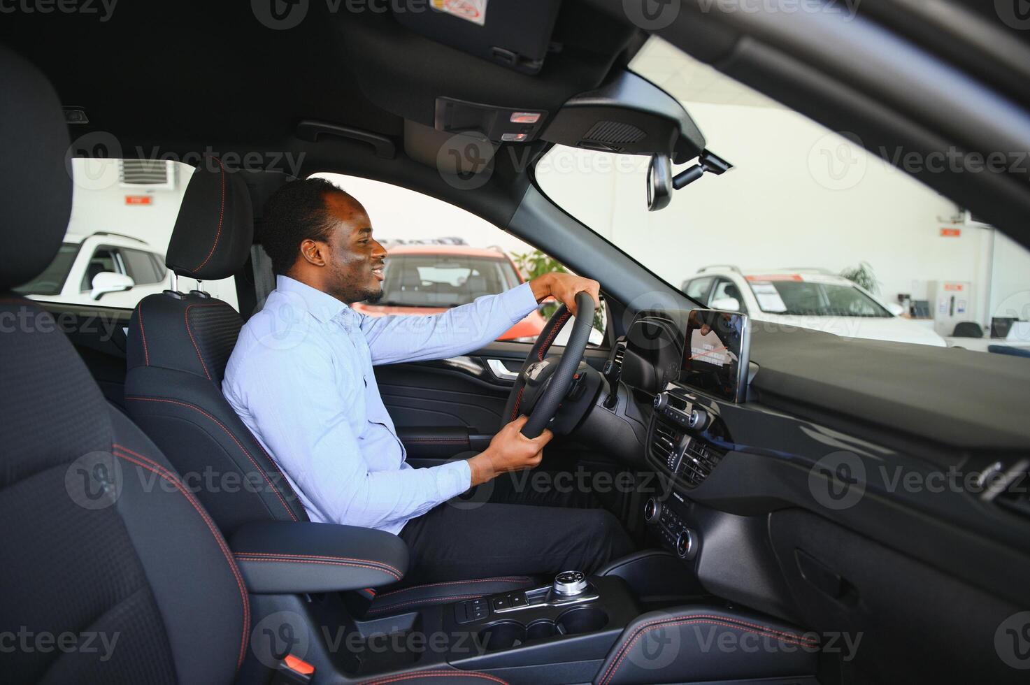 voiture propriétaire. joyeux afro gars souriant, séance dans Nouveau voiture conduite de concession magasin photo