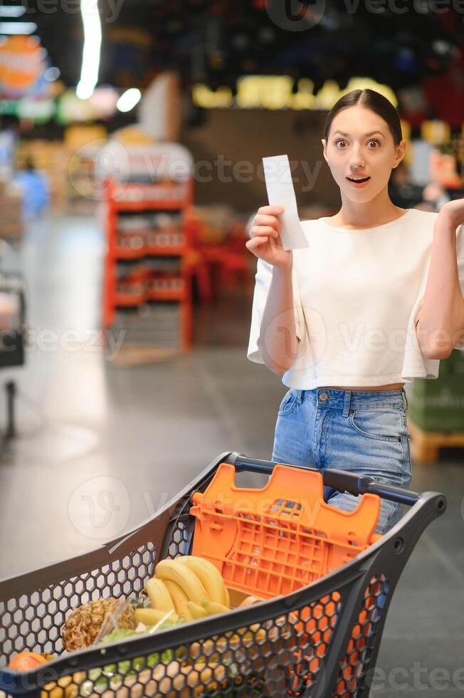 confus et dérangé femme avec une vérifier dans épicerie magasin. photo