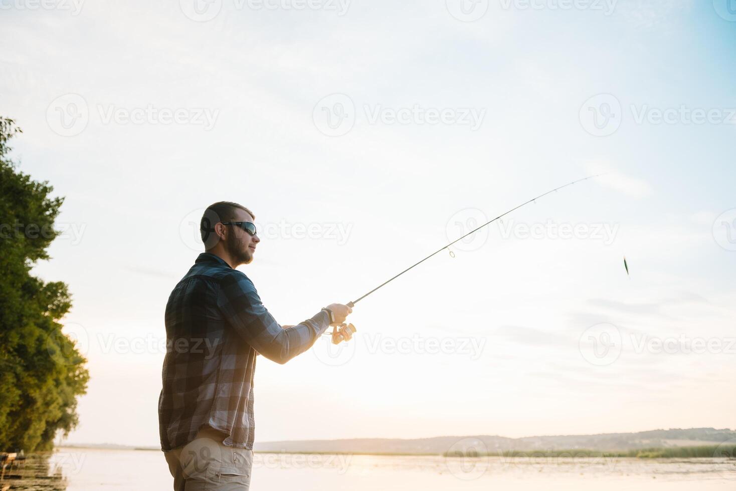 pêcheur homme pêche avec filage barre sur une rivière banque à brumeux brumeux lever du soleil. pêcheur avec filage. filage concept. photo