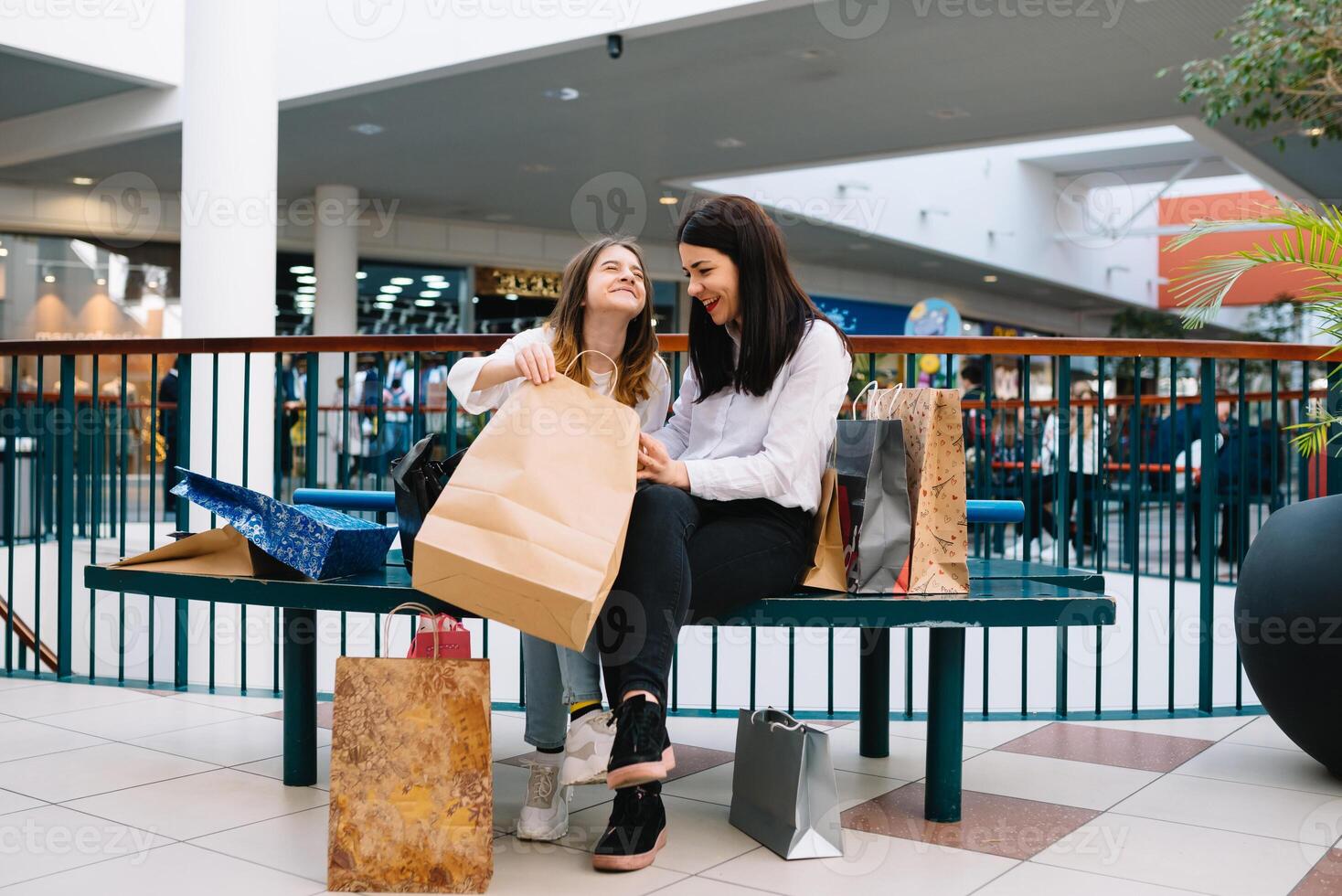 magnifique Jeune maman et adolescent fille sont en portant achats Sacs, achats dans centre commercial. famille achats photo